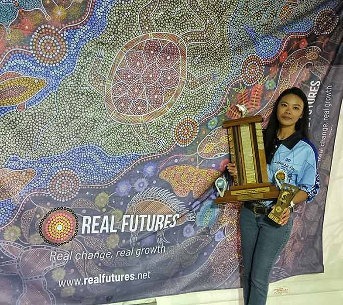 Rona with her trophy from Carnar-Fin 2022 with Real Futures banner in background
