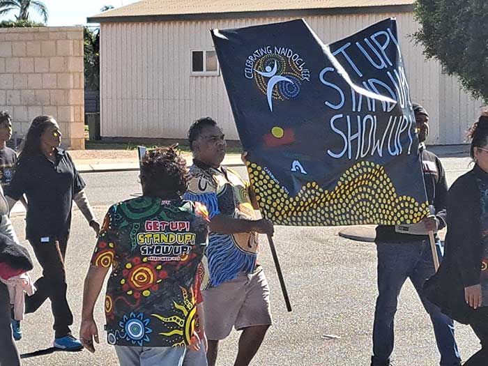 NAIDOC Week banner and the Carnarvon community during the NAIDOC March in Carnarvon.