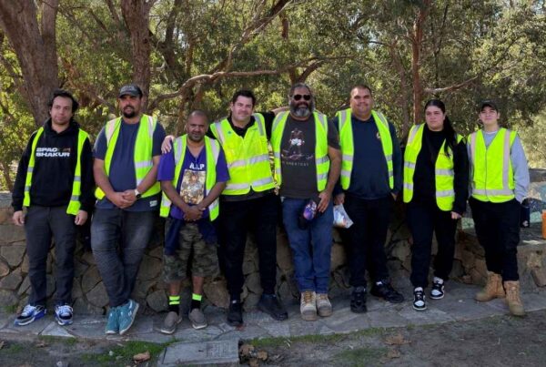 Group of Indigenous job seekers wearing high-visibility safety vests outdoors after completing traffic control training